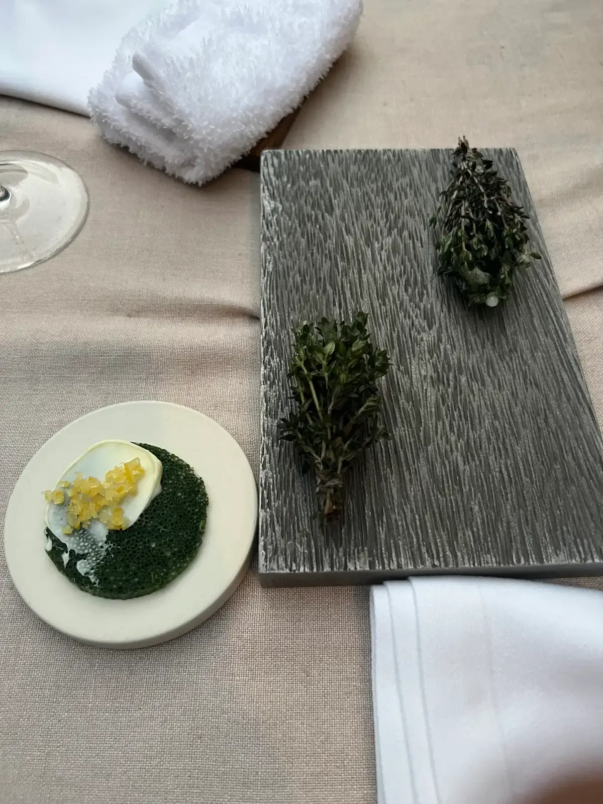 A dark sculptural bite on gold ceramic beside a red fruit tartlet at Mugaritz