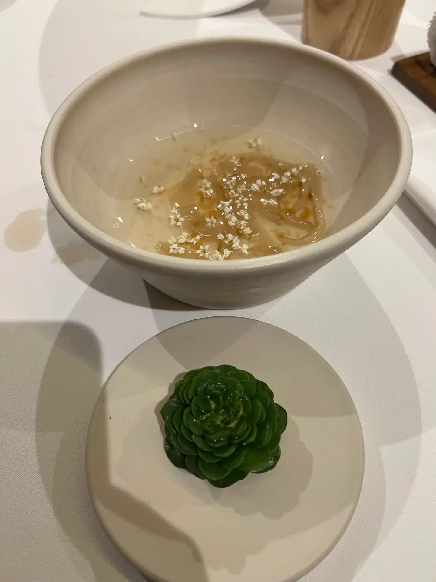Greens and a soft-textured bite on a dark wooden serving board at Mugaritz