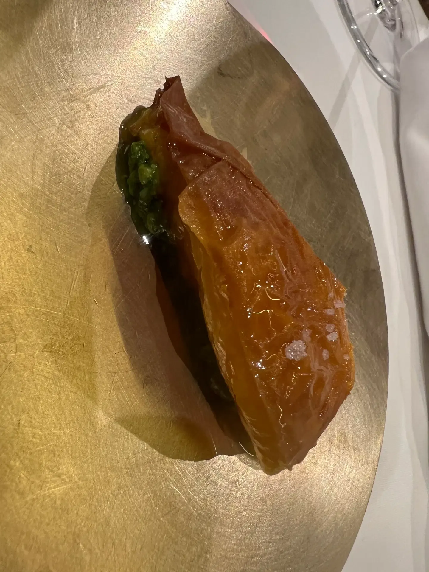 A glossy amber course with a green centre on a gold plate at Mugaritz